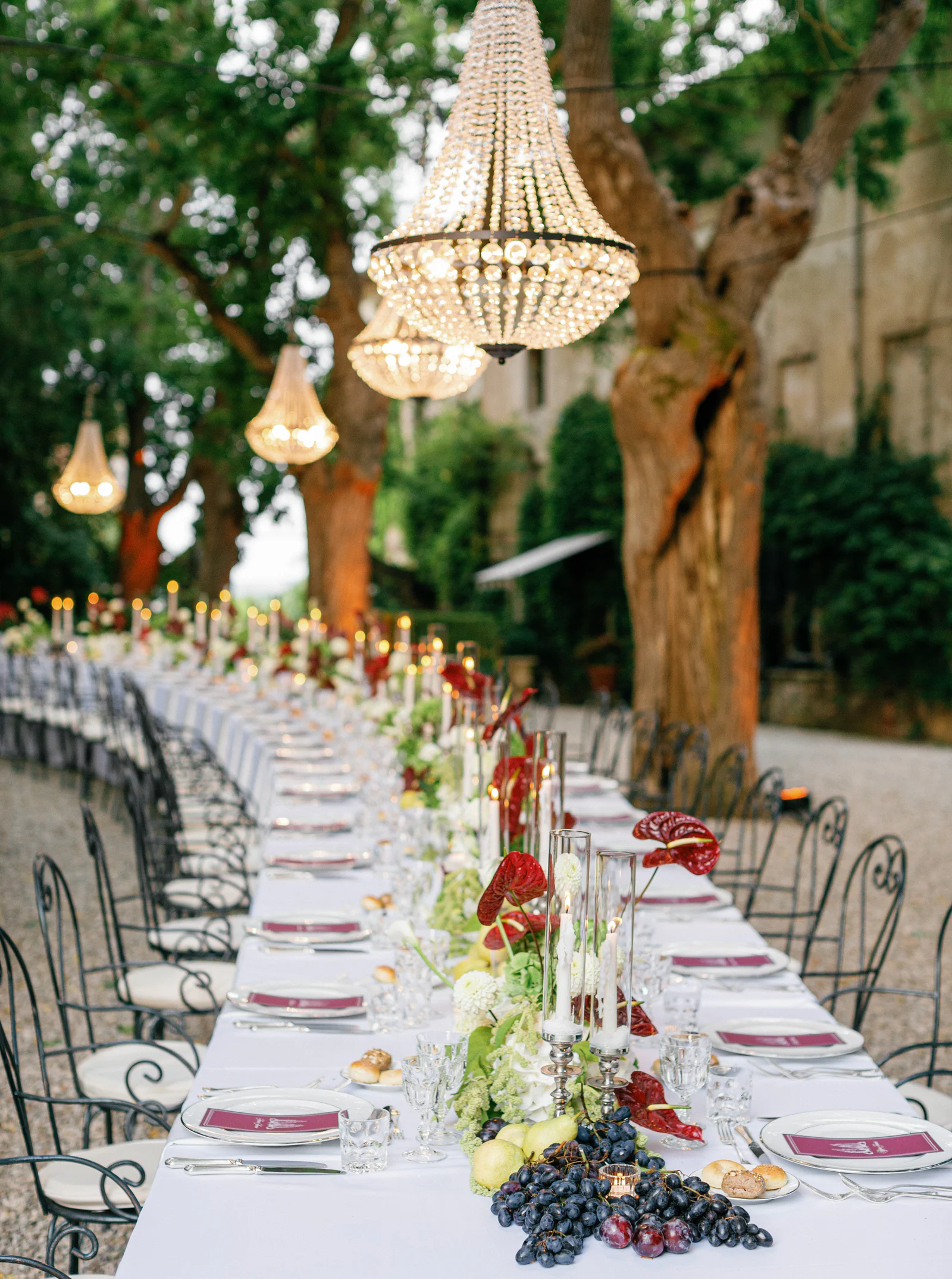 Curving dinner table under crystal chandeliers hung in the olive trees at Borgo Stomennano, Chianti