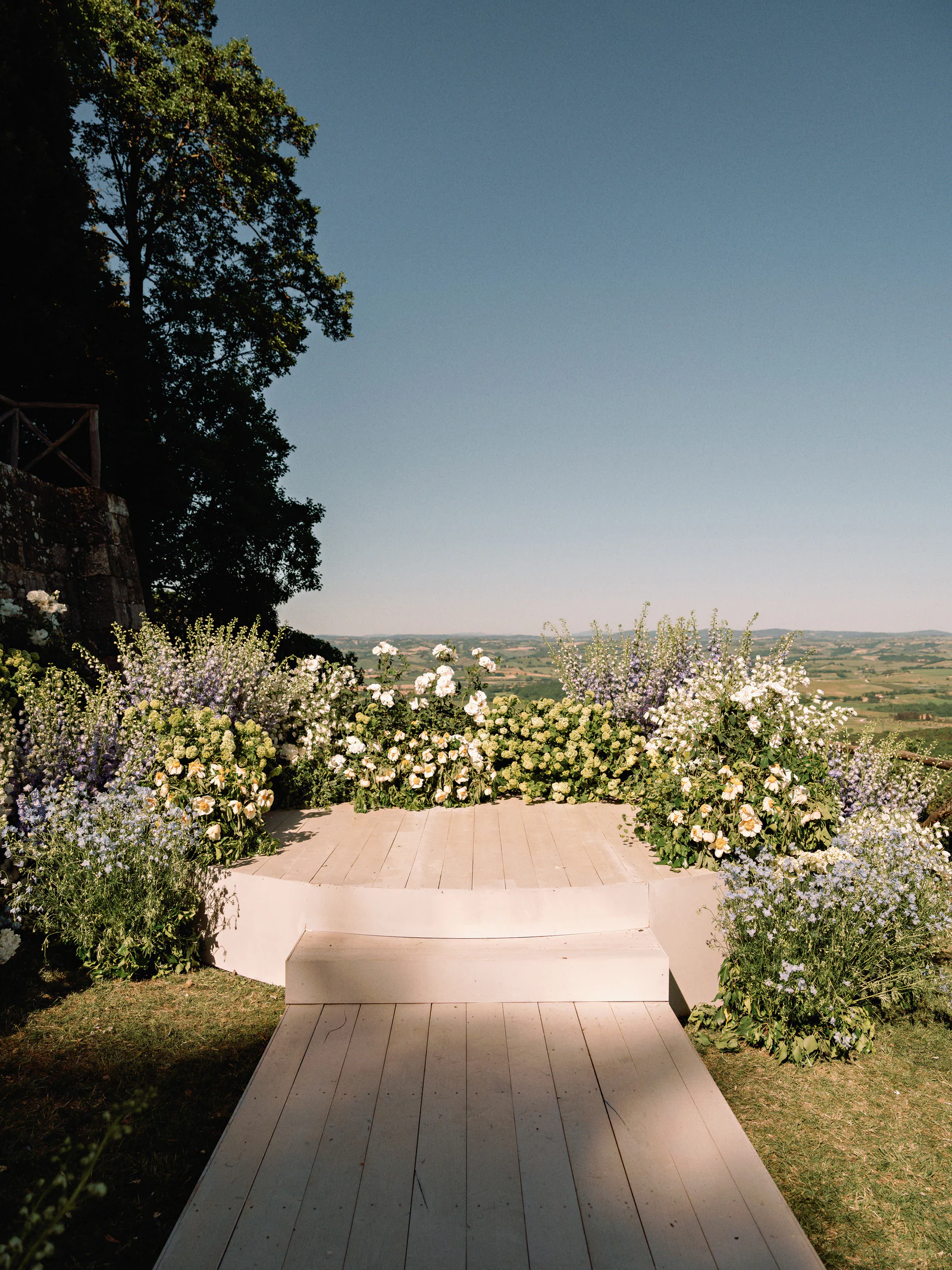 Ceremony aisle laid with white and blue florals above the Val d'Orcia at Castiglion del Bosco, A Rosewood Hotel, Tuscany